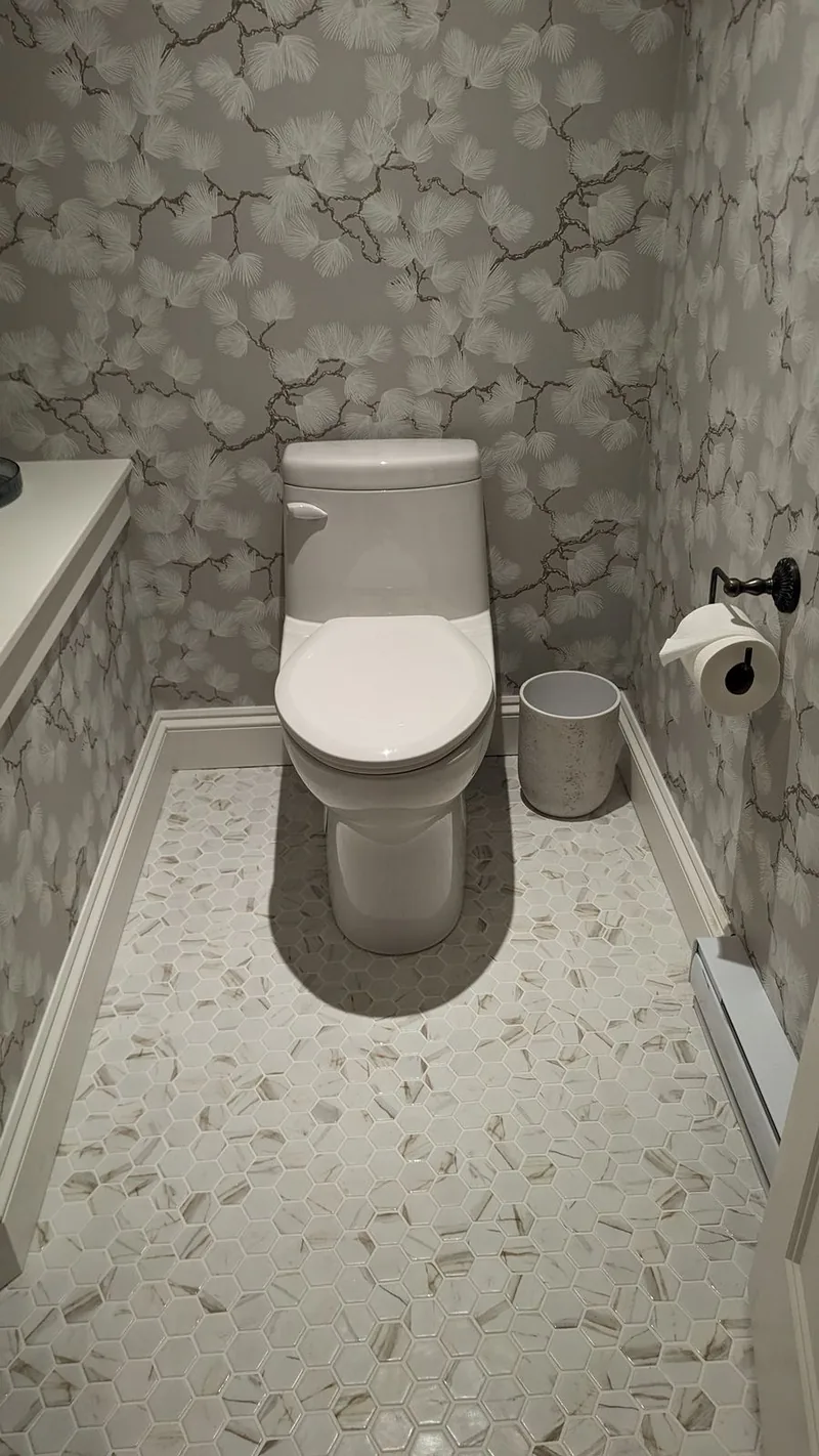 Finished bathroom with botanical wallpaper, hexagonal marble tile, and modern toilet