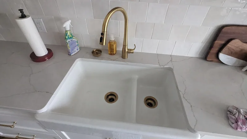 Farmhouse kitchen sink with brass faucet and quartz countertop