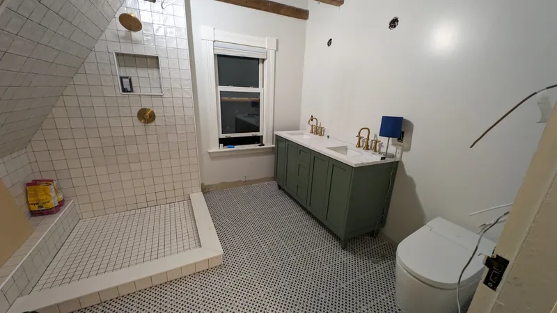 Bathroom with a green double vanity, brushed-gold faucets, and a white-tiled walk-in shower