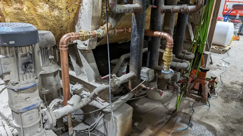 Mechanical room with a pump, copper manifold piping, and a water treatment system