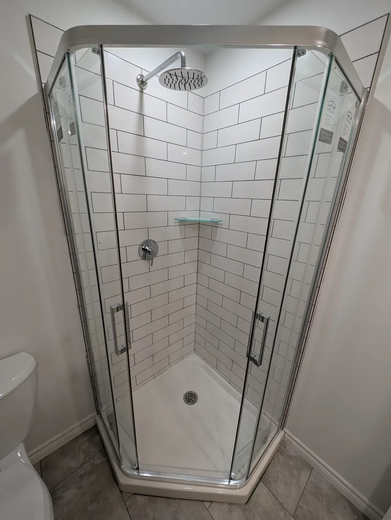 Corner glass shower enclosure with white subway tile and a chrome rainfall shower head